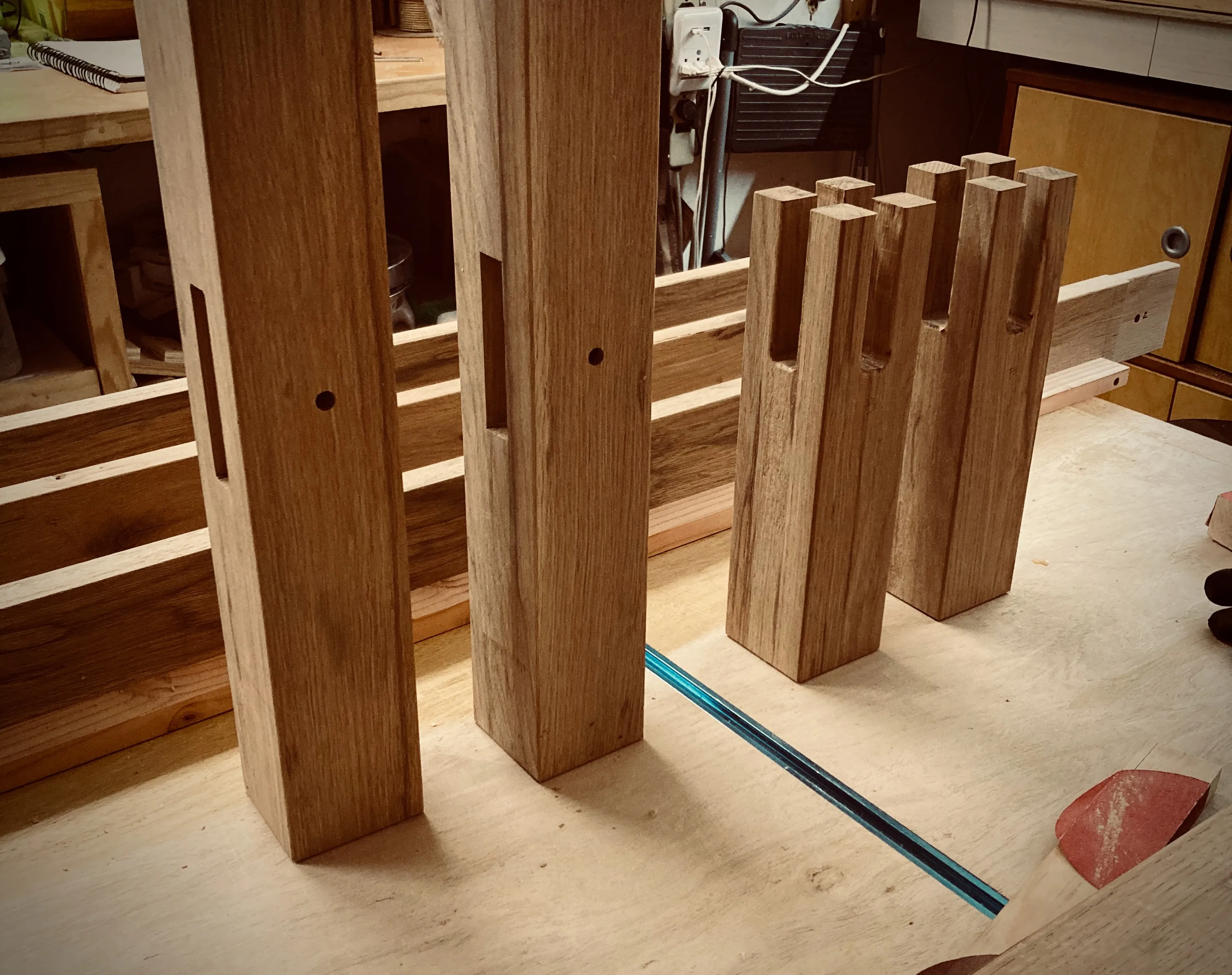Oak boards and mortise-tenon joint pieces laid out on the workbench for the bed frame