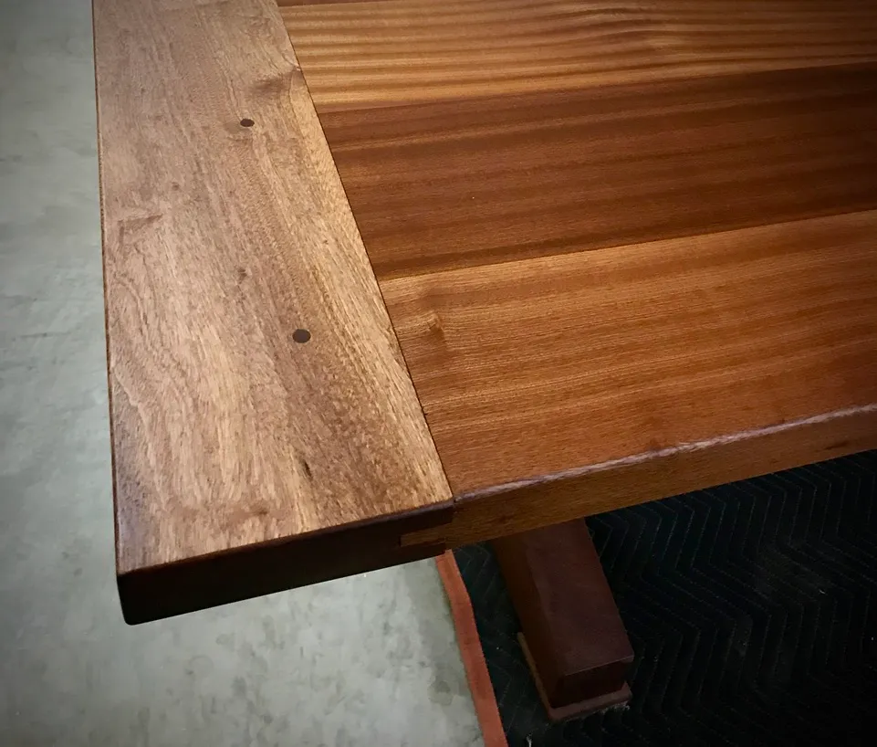 Finished African mahogany trestle table with tapered legs, in a sunlit room