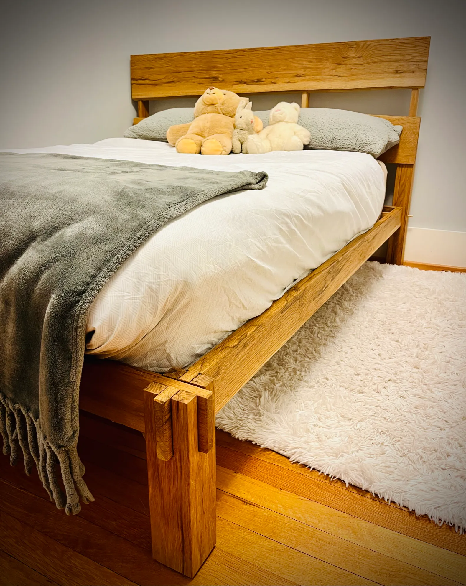 Live edge white oak bed with stuffed animals on the pillows, in a cozy bedroom