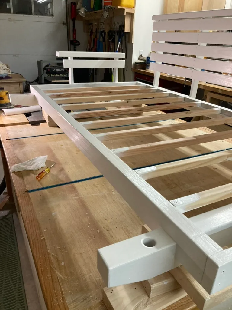White-painted porch swing slat frame partially assembled on the workbench