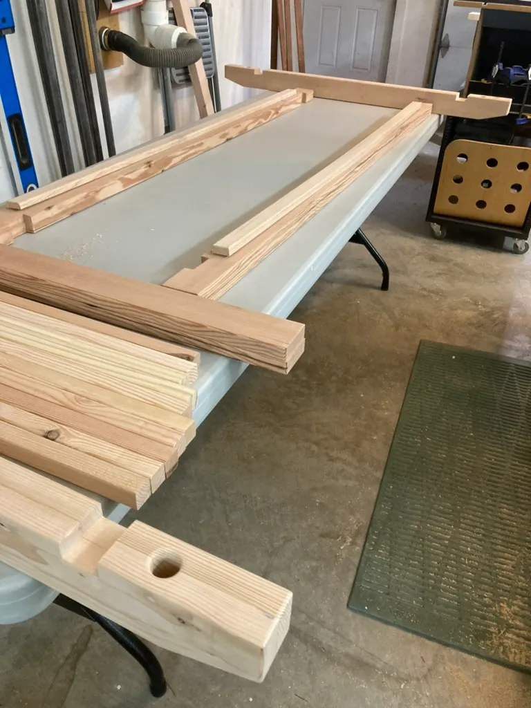 Reclaimed wood boards and frame parts for the porch swing, laid out on sawhorses in the garage