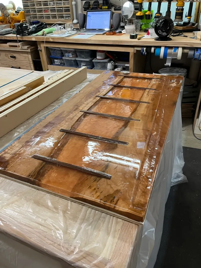Pouring amber epoxy into the river table's inlay channels