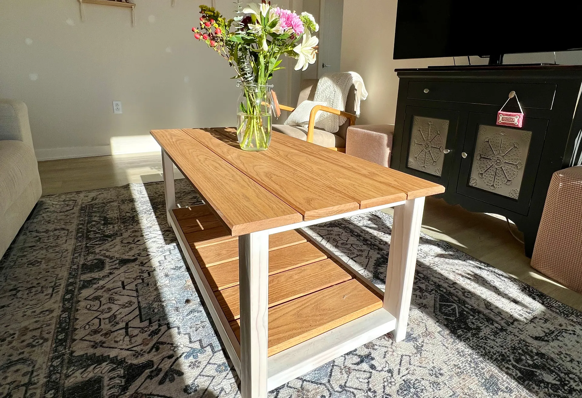White oak coffee table with slatted lower shelf, shown from a three-quarter angle in a living room
