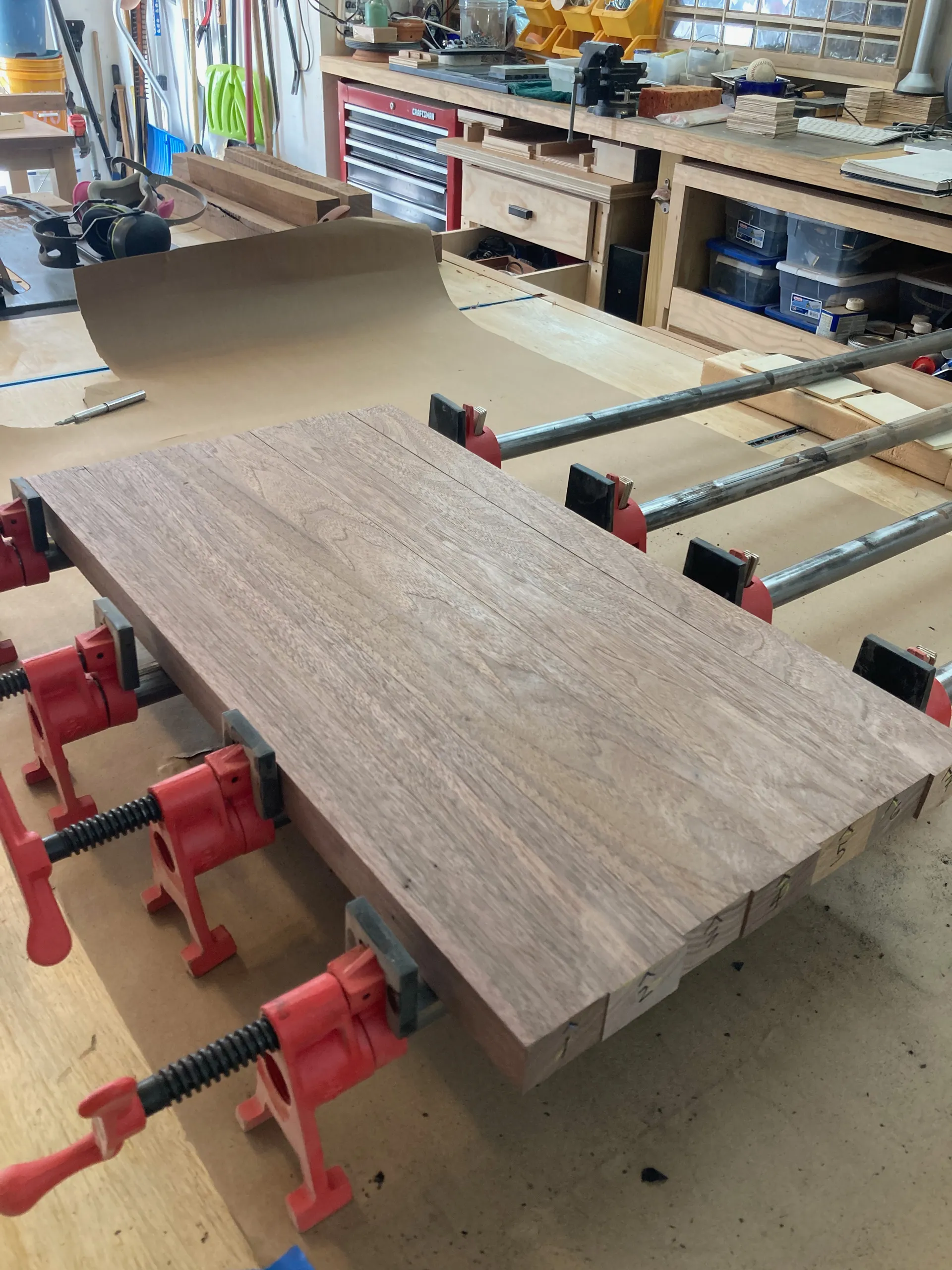 Raw walnut and cherry boards clamped for glue-up on the workbench for the spice rack