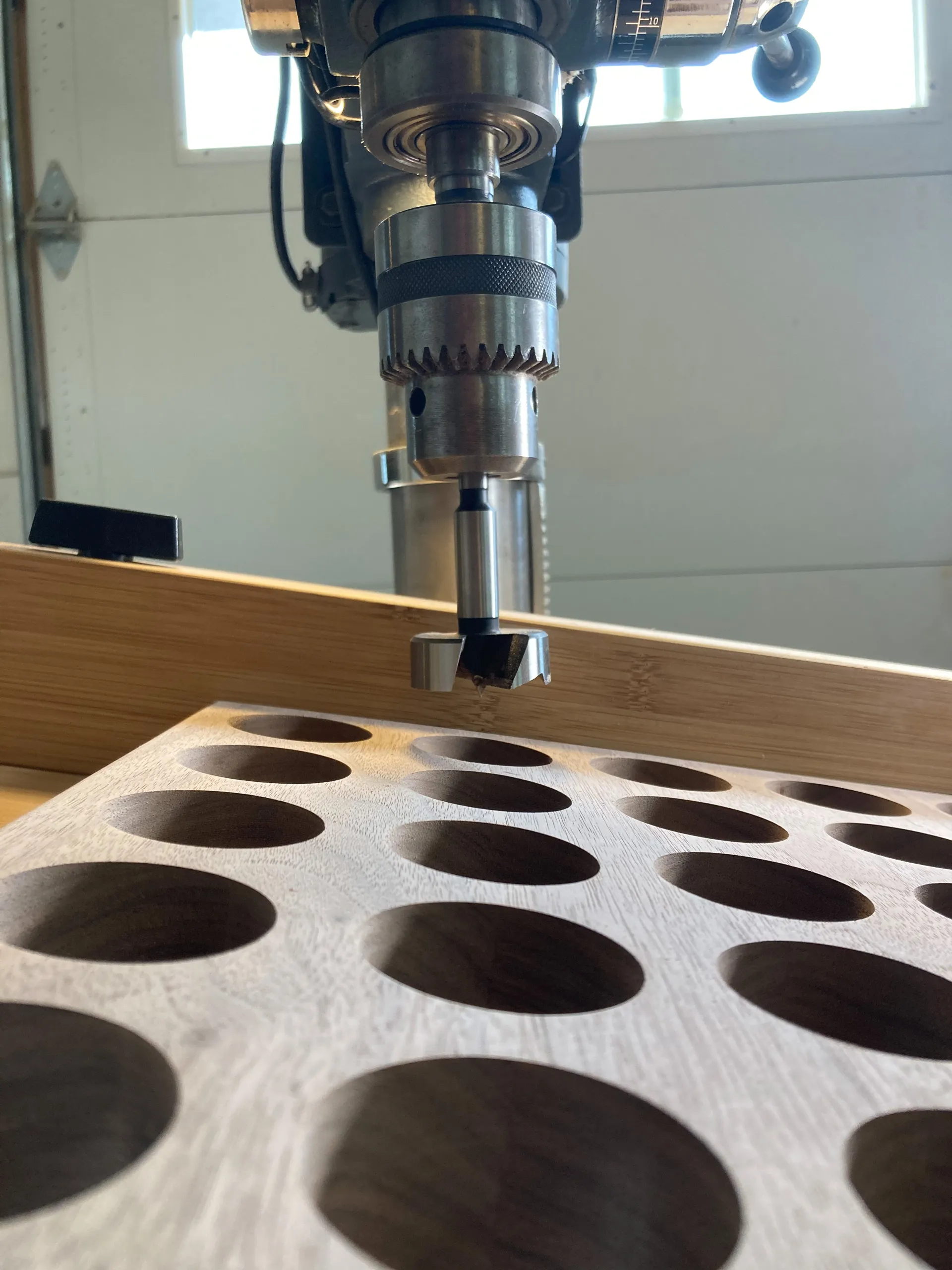 Close-up of the finished walnut spice rack panel with two rows of drilled circular holes for spice jars