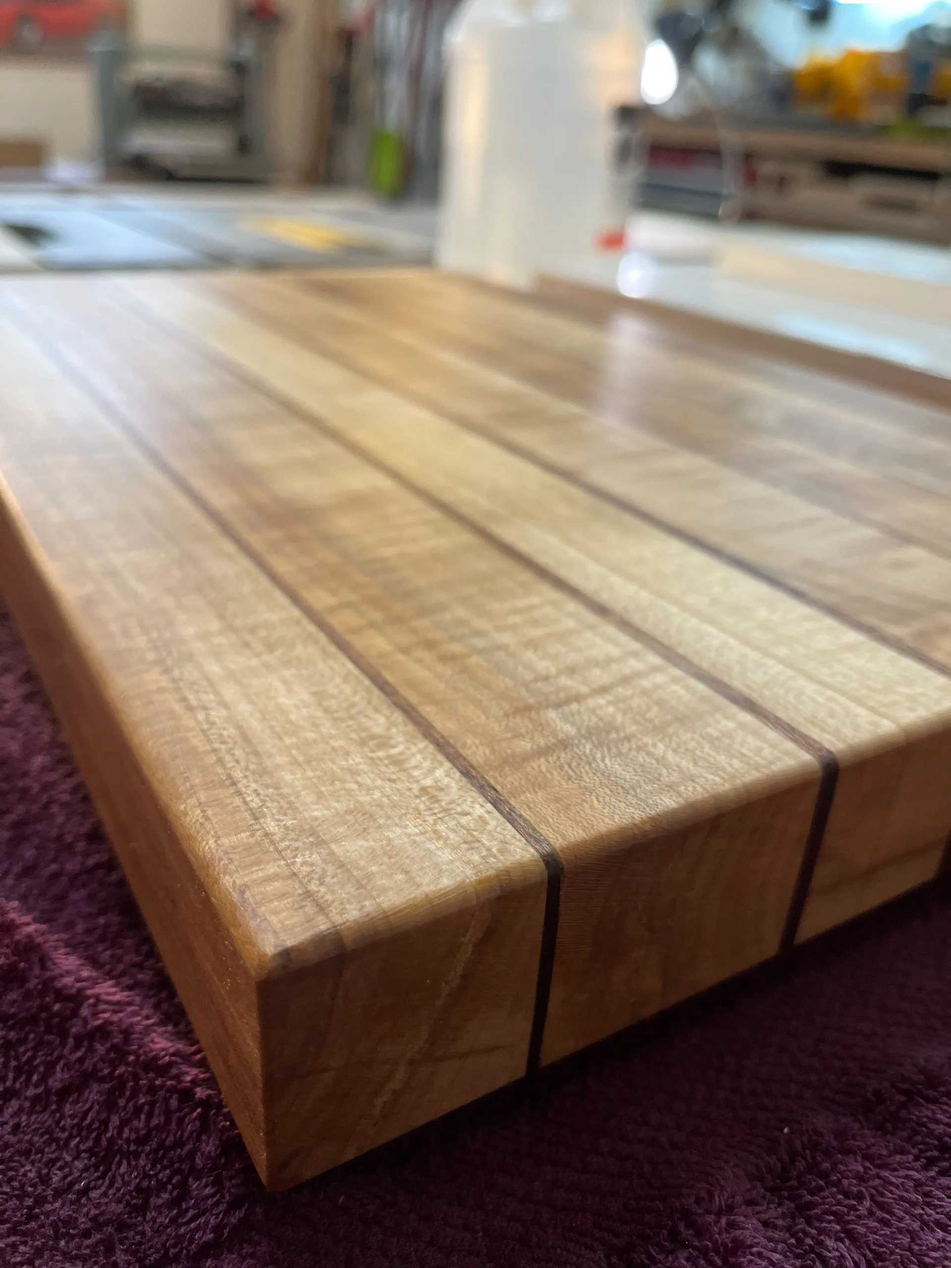 Close-up corner detail of the finished sugar maple and mahogany striped cutting board, showing the inlay lines