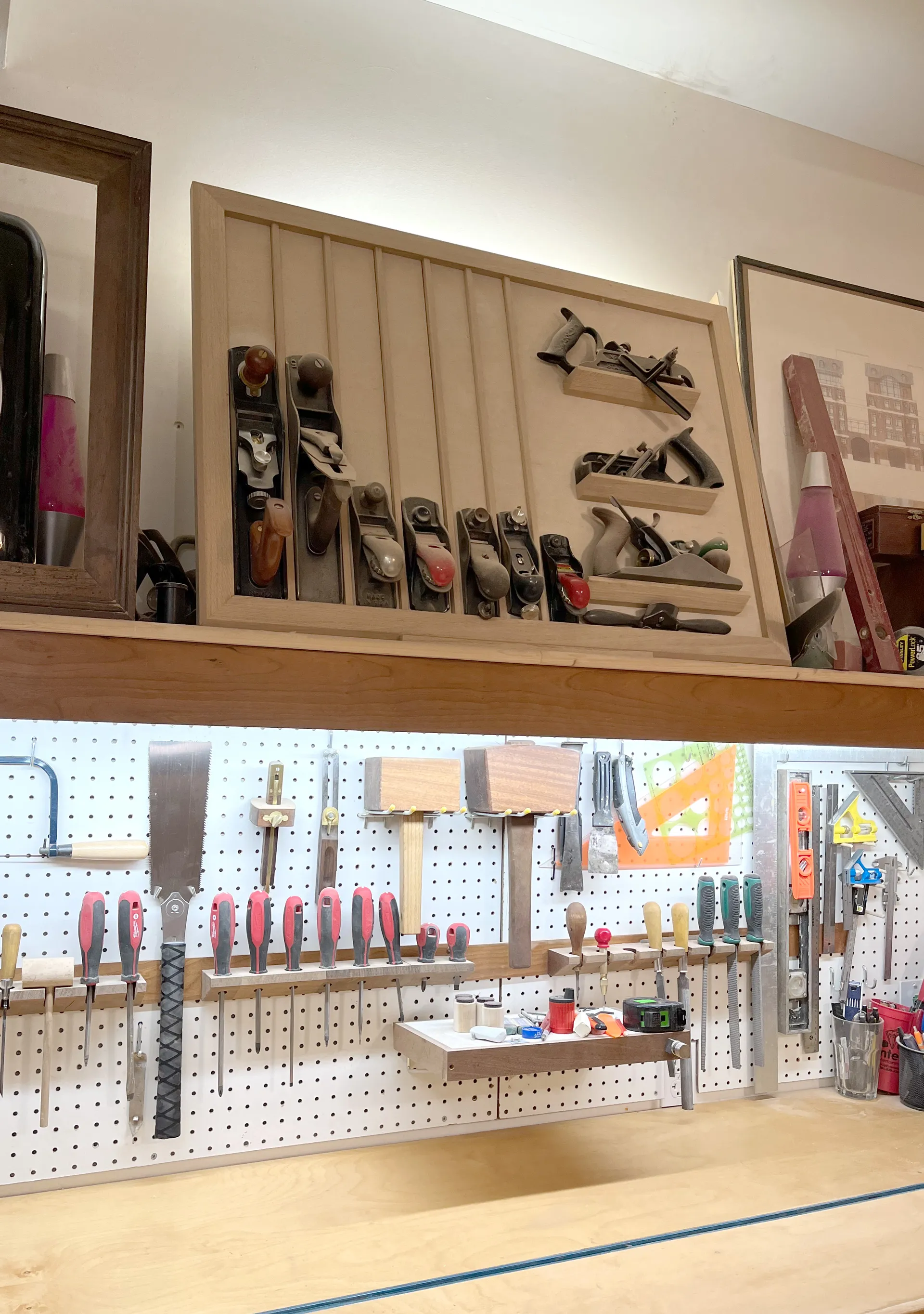 Pegboard wall neatly organized with hand planes, mallets, chisels, screwdrivers, and squares, each tool in its own labeled spot