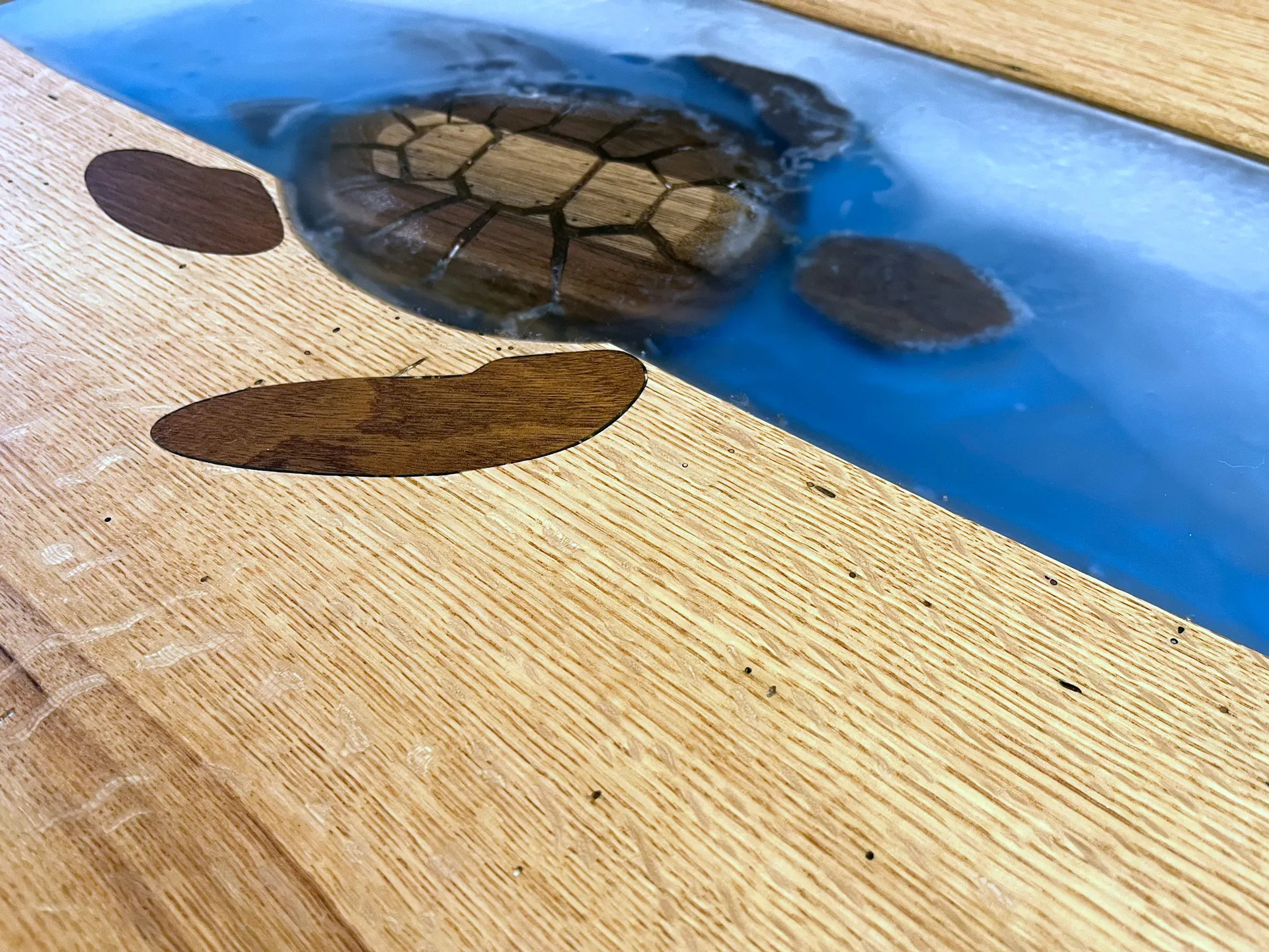 Finished white oak coffee table with a blue epoxy river and a carved wood sea turtle inlay