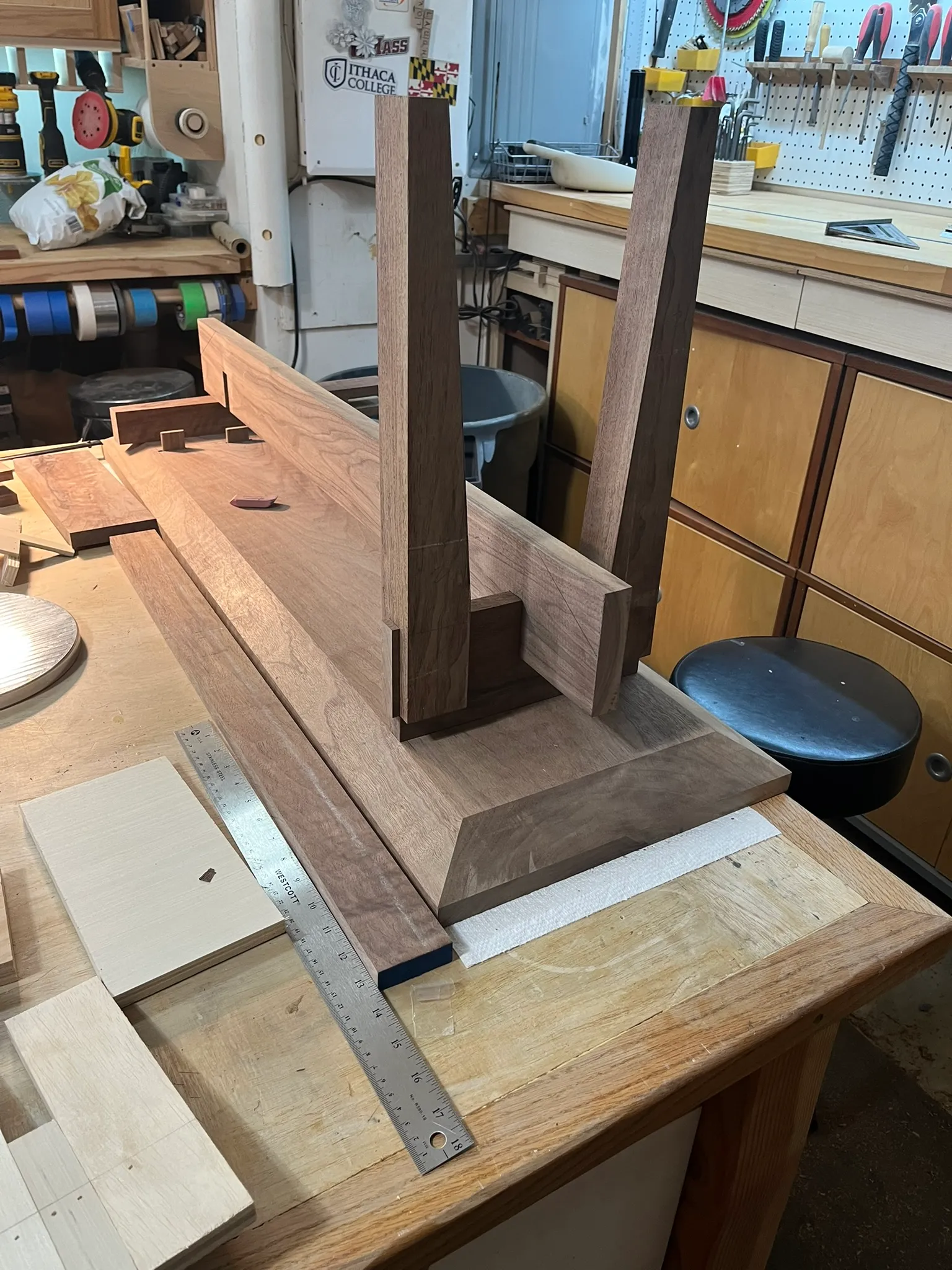 Assembled walnut entryway bench legs and stretcher joined on the workbench, mortise and tenon joinery visible