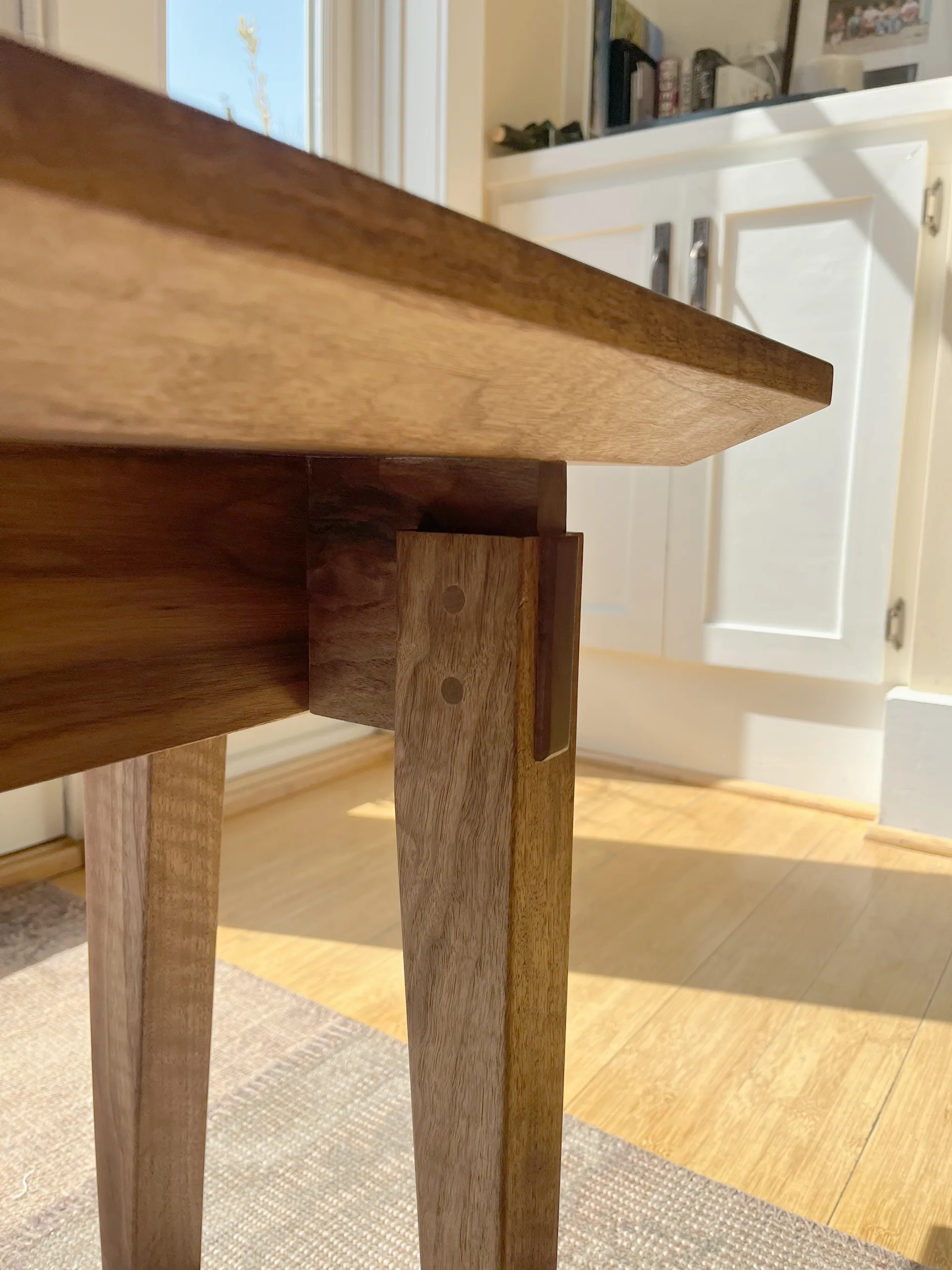 Walnut entryway bench shown from a front angle on an area rug