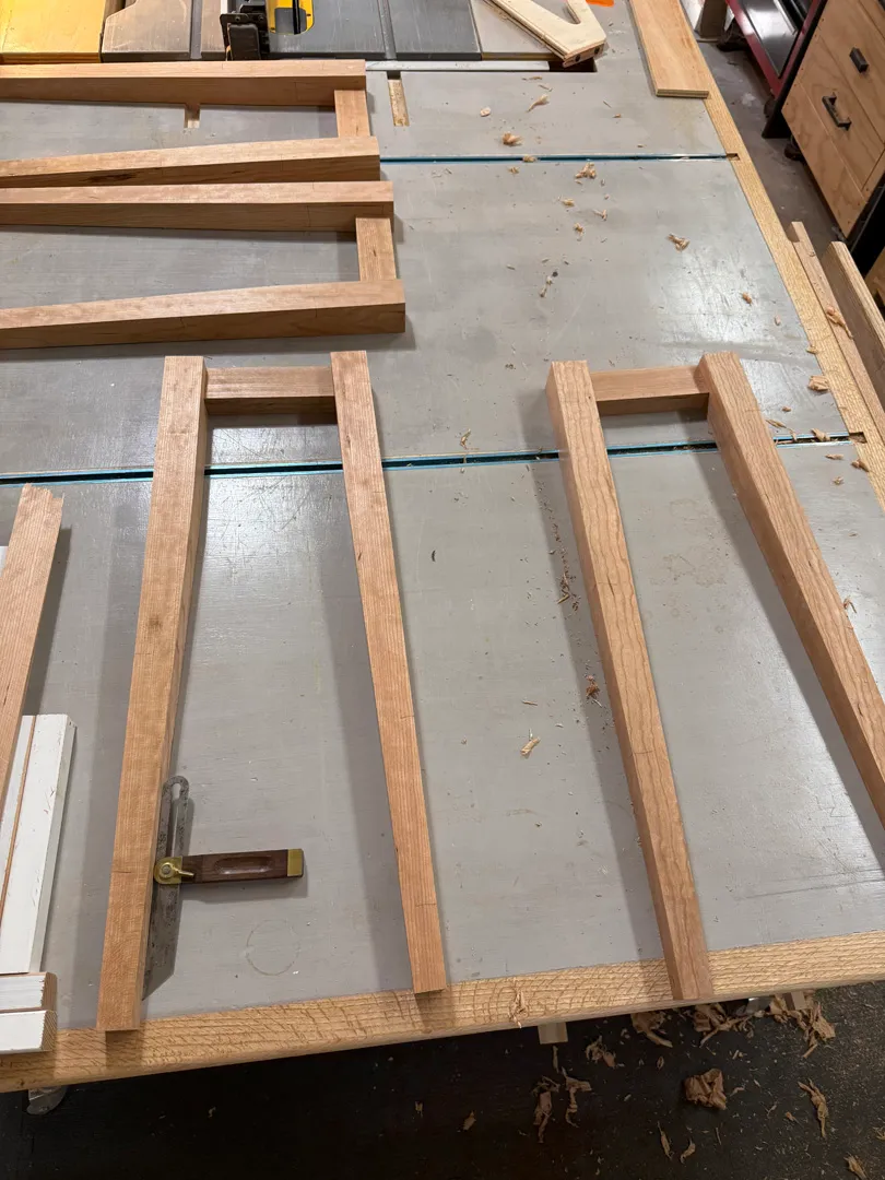 Raw cherry boards and stool frame pieces cut and laid out on the workbench