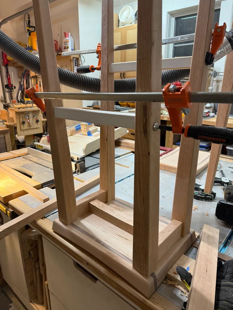 Cherry bar stool frame with stretchers clamped for glue-up using orange and blue bar clamps
